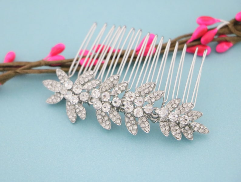 May include: Silver hair comb with three crystal leaf designs. The comb has a row of teeth on the back.