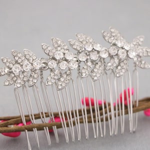 May include: Silver hair comb with a row of crystal leaves. The comb has a silver finish and is decorated with clear rhinestones.