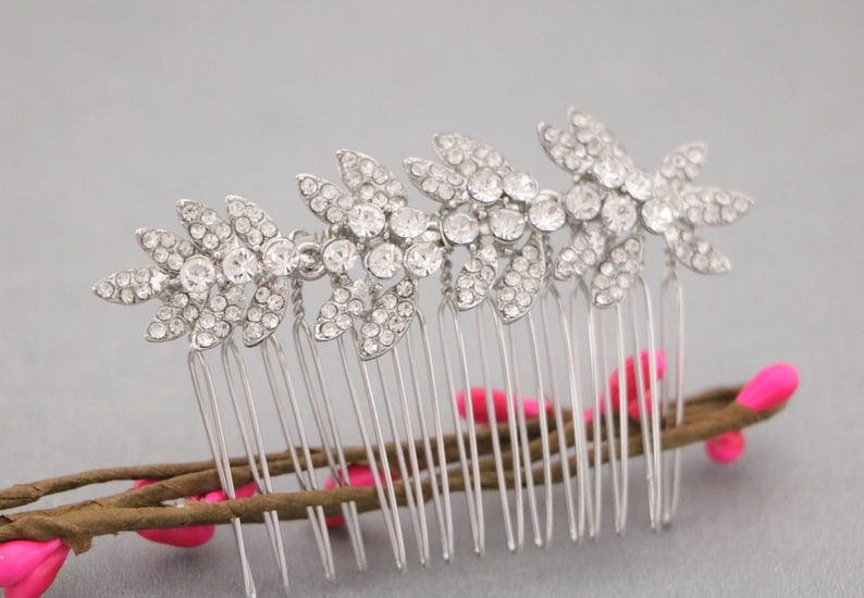May include: Silver hair comb with a row of crystal leaves. The comb has a silver finish and is decorated with clear rhinestones.