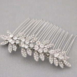 May include: Silver hair comb with three crystal flower designs. The comb has a row of teeth on the back.
