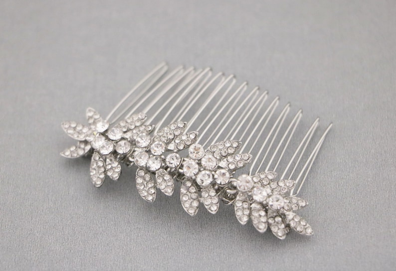 May include: Silver hair comb with three crystal flower designs. The comb has a row of teeth on the back.