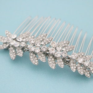 May include: Silver hair comb with a row of crystal rhinestones in a floral design.