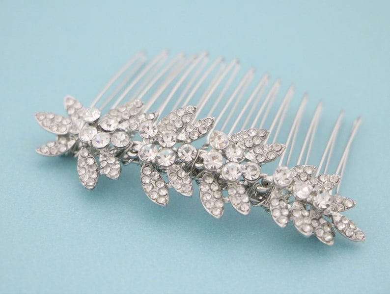 May include: Silver hair comb with a row of crystal rhinestones in a floral design.
