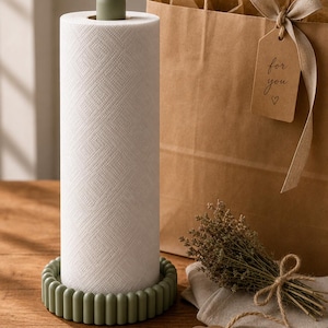 May include: A white kitchen roll on a green holder with a matching green top. A brown paper gift bag with a tag that says "for you" is in the background. A small bundle of dried flowers and a blank tag are also present.