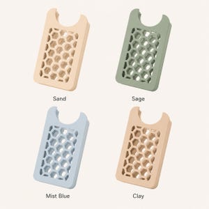May include: Four phone card holders in sand, sage, mist blue, and clay colors. Each holder has a honeycomb pattern and a curved top. The names of the colors are printed below each holder.