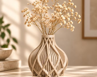 Può includere: Un vaso color beige con una complessa struttura a reticolo aperto caratterizzata da nervature verticali curve e intersecanti. Il vaso ha una base ampia e arrotondata che si restringe verso un collo stretto e contiene un bouquet di fiori secchi.