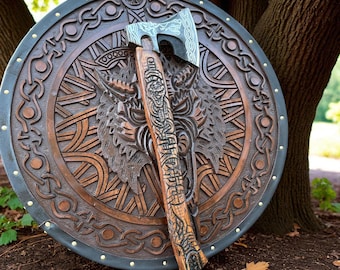 May include: A wooden shield and axe set. The shield is round with a dark brown finish and intricate carvings of a wolf's head and Celtic knot patterns. The axe has a silver blade and a wooden handle with detailed carvings.