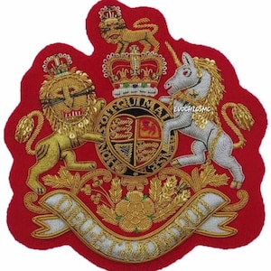 May include: A red embroidered patch featuring a royal crest with a lion and unicorn flanking a shield. The crest includes a crown, banner, and intricate gold and silver thread detailing. The patch is approximately 6 inches wide.
