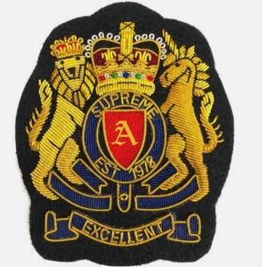 May include: Embroidered patch with a black background. The patch features a gold lion and horse flanking a central emblem with the word "SUPREME" and the letter "A". The text "EST 1978" and "EXCELLENT" are also present.