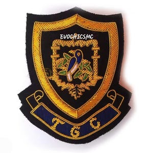 May include: A black and gold embroidered shield-shaped patch. The patch has a central design of a bird and foliage, with the text "EVOGHICMC" at the top and "TGC" on a blue banner at the bottom.