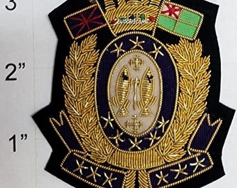May include: A black embroidered patch featuring a gold crown, two flags, and a central oval with two fish and a sword. The design includes gold laurel leaves and stars on a dark blue background. A ruler shows the patch is approximately 3 inches tall.