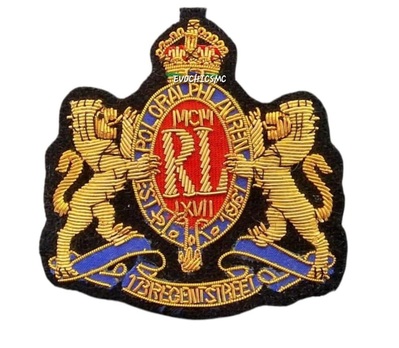 May include: A black embroidered patch featuring a gold crown above a red oval crest with the letters RL and Roman numerals MCMLXVII. Two gold lions flank the crest, which is surrounded by text reading POLO RALPH LAUREN and 173 REGENT STREET.