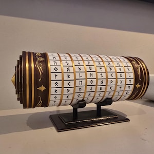 May include: A cylindrical, brown and gold decorative object with rotating panels, each displaying a unique symbol. The object is mounted on a black stand. The panels are white with black symbols and gold borders.