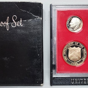 May include: A 1982 United States Proof Set in a black box. The box reads "United States Proof Set" and "1982" in white script. The set includes six coins displayed on a red background within a clear case.
