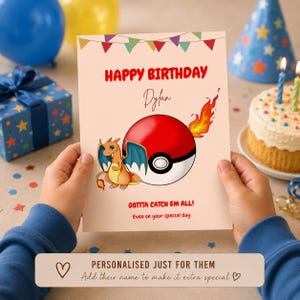 May include: A rectangular birthday greeting card featuring a red and white Poké Ball with a flame, a cartoon dragon character, and colourful bunting. The text reads HAPPY BIRTHDAY, Dylan, GOTTA CATCH EM ALL!, and Even on your special day in red and black.