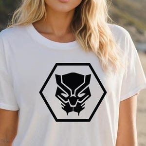 May include: White t-shirt featuring a black graphic of a panther's face within a black hexagon. The design is centered on the shirt. The shirt is made of a soft material.