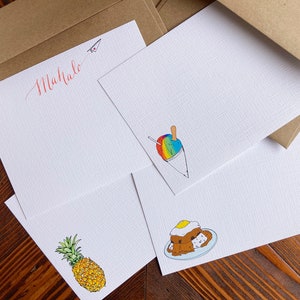 Könnte beinhalten: Vier leere weiße Notizkarten mit verschiedenen Illustrationen. Die oberste Karte trägt das Wort "Mahalo" in roter Kursivschrift. Die zweite Karte zeigt ein Regenbogen-Shave-Eis. Die dritte Karte zeigt eine Ananas. Die vierte Karte zeigt einen Teller mit Essen mit einem Spiegelei darauf.