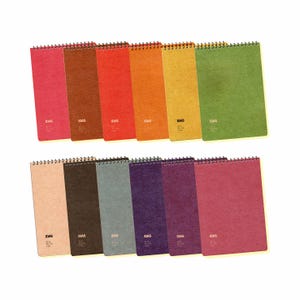 May include: A collection of spiral-bound notebooks in various colors, including pink, brown, red, orange, yellow, green, beige, dark brown, blue-gray, purple, and magenta. Each notebook has the word "IDAS" printed on the bottom left corner.