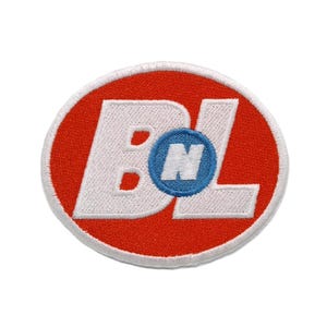 May include: An oval-shaped embroidered patch featuring a vibrant red background with a white border. The design displays large white letters B and L, with a smaller blue circular emblem in the center containing a white letter N.
