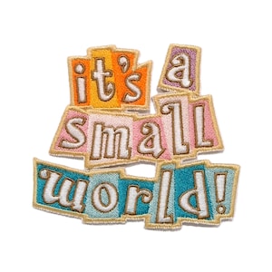 Może przedstawiać: Haftowana naszywka z napisem "it's a small world!" wykonanym białą, stylizowaną czcionką. Słowa umieszczono na tle nakładających się na siebie prostokątnych kształtów w odcieniach pomarańczu, różu i błękitu, obszytych złotą nicią.