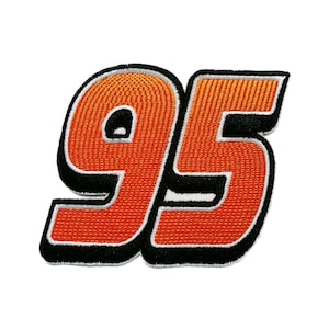 Könnte beinhalten: Ein gestickter Aufnäher mit der Zahl 95 in einer fetten Blockschrift. Die Ziffern sind in einem leuchtenden Orange-Verlauf gehalten, der nach oben hin in ein helleres Gelb-Orange übergeht, umrandet von dicken weißen und schwarzen Rändern.