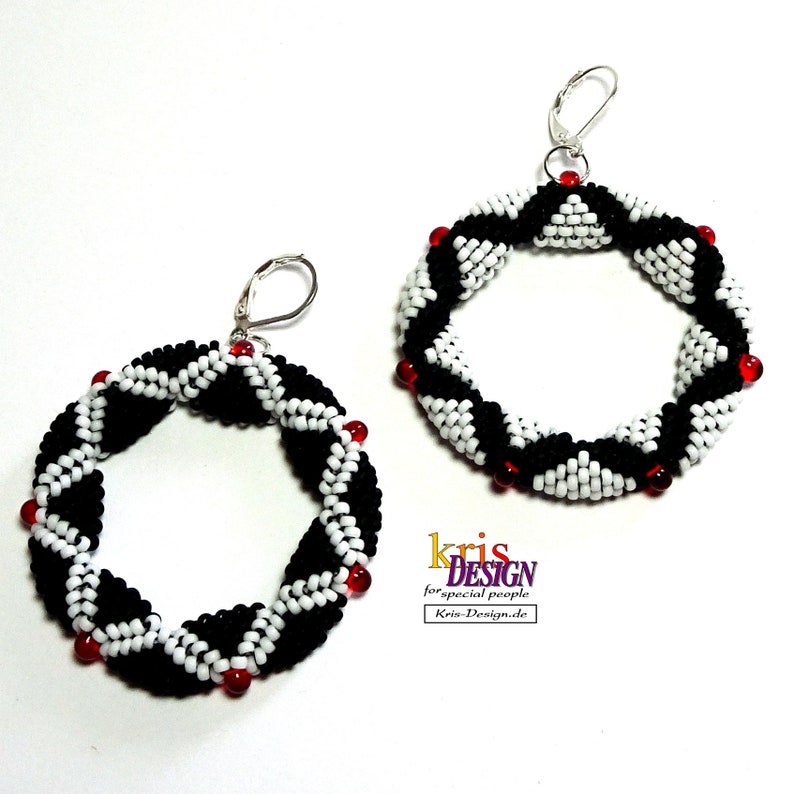 May include: A pair of black and white beaded hoop earrings with red accents. The earrings are made with small beads and have a geometric pattern.