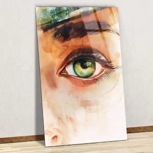 Puede incluir: Una impresión artística rectangular que presenta un primer plano de un ojo humano. El ojo es de un verde vibrante con largas pestañas oscuras. La obra de arte tiene un estilo de acuarela con tonos cálidos y terrosos y un toque de verde.