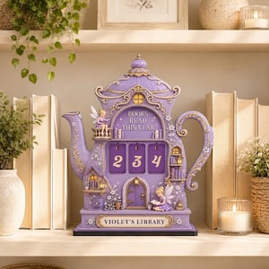 Pode incluir: Um expositor decorativo em forma de bule roxo intitulado Violet's Library com o texto Books Read This Year. Possui três espaços para números, duas figuras de fadas, pequenas prateleiras com livros, uma porta e detalhes florais em lilás.