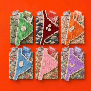 May include: Six rectangular notebooks with floral and wave patterned covers, each featuring a triangular crochet pocket in green, maroon, orange, blue, pink, or purple. Each pocket holds a small notepad, a pen, and a decorative sticker.