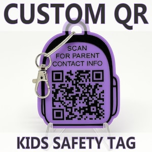 Könnte beinhalten: Ein lila rucksackförmiger Anhänger mit einem QR-Code und dem Text "SCAN FOR PARENT CONTACT INFO". Der Anhänger ist an einem silbernen Verschluss befestigt und trägt die Aufschrift "CUSTOM QR" und "KIDS SAFETY TAG".