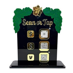 May include: Black acrylic sign with gold lettering and accents. The sign reads "Scan or Tap" and features QR codes and symbols for payment options. Green leaf and flower accents adorn the top.