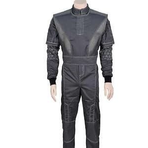 May include: A gray jumpsuit with a high collar and long sleeves. The suit features light gray accents on the shoulders, chest, and sleeves, with white stitching details. Black cuffs are visible at the wrists. The jumpsuit is displayed on a mannequin.