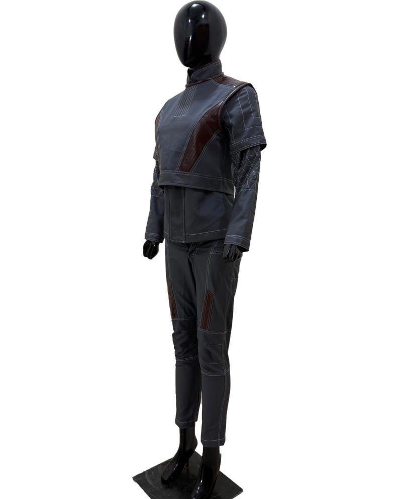 May include: A gray and burgundy two-piece outfit displayed on a mannequin. The outfit includes a high-collared jacket with burgundy accents and matching pants. White stitching details the seams. The mannequin is black and stands on a black base.