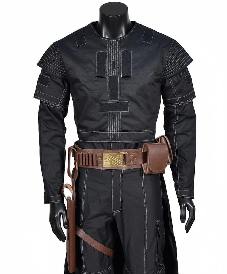 May include: Black costume with white stitching, including a long-sleeved top with shoulder accents and matching trousers. A brown leather belt with a gold buckle and a holster are also included. The costume is displayed on a mannequin.