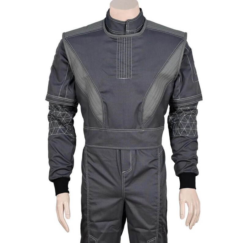 May include: A gray racing suit with white stitching and geometric patterns on the sleeves. The suit has a high collar, a belt, and black cuffs. The suit is displayed on a mannequin.