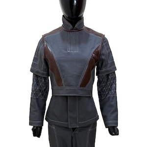 May include: A gray and brown two-piece outfit. The jacket has a high collar, brown shoulder accents, and white stitching details. The sleeves feature a diamond pattern. The pants have brown accents at the knees.