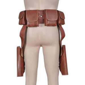 May include: Brown leather utility belt with multiple pouches and two holster-style leg straps. The belt features a series of rectangular pouches and is designed to be worn around the waist. The leather appears to be a medium brown color.
