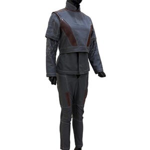 May include: A gray two-piece outfit displayed on a mannequin. The jacket has brown accents on the shoulders and chest, with white stitching. The pants are gray with brown accents and white stitching. The outfit is designed with a futuristic aesthetic.