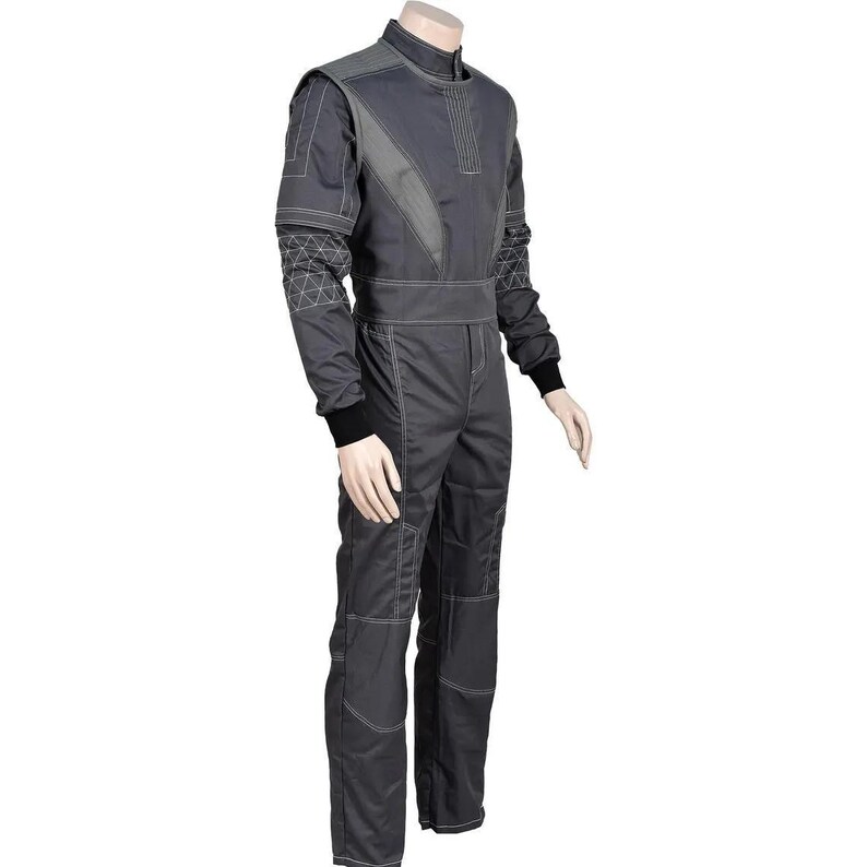 May include: A dark gray racing suit with contrasting light gray panels and white stitching. The suit features a high collar, long sleeves with black cuffs, and reinforced knee panels. The design includes geometric patterns on the shoulders and upper arms.