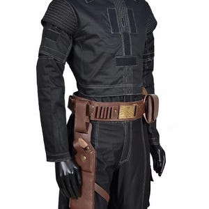 May include: Black costume with a round-neck top, white stitching, and a brown belt with a gold buckle. The costume includes a holster and a matching brown leather sheath. The outfit is displayed on a mannequin.