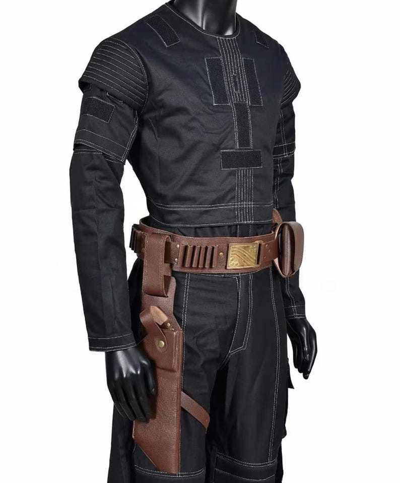 May include: Black costume with a round-neck top, white stitching, and a brown belt with a gold buckle. The costume includes a holster and a matching brown leather sheath. The outfit is displayed on a mannequin.