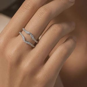 May include: A silver-toned ring guard set featuring two chevron-shaped bands. Each band is crafted with a polished metal finish and is adorned with a row of small, clear, round-cut stones set along the top edge of the V-shaped design.
