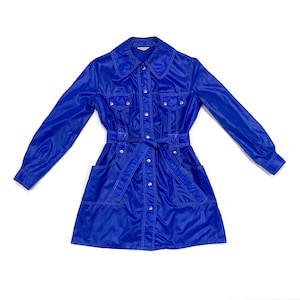 May include: A vibrant blue dress with long sleeves, a collared neckline, and a matching belt. The dress features button closures, two chest pockets, and two hip pockets. The dress is made of a shiny, possibly nylon, material.