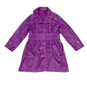 May include: A vintage purple raincoat with white stitching details. The coat features a collared neckline, button-down front, and pockets. The waist is cinched with a sewn-in belt. The sleeves have buttoned cuffs.