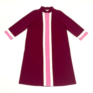 May include: A burgundy dress with a high collar and three-quarter sleeves. The dress features a vertical stripe of white and pink down the front, with matching pink and white cuffs. The dress has a zipper closure.