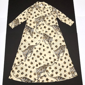 May include: A long, cream-colored dress with a leopard print design. The dress features a collared neckline, long sleeves, and a full-length zipper. The leopard print includes brown and black spots and floral accents.