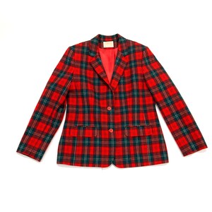 May include: A red, green, and gold plaid blazer with a two-button closure and two front pockets. The blazer has a red lining and a notched collar. The garment is laid flat on a white surface.