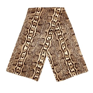 May include: A brown and tan snakeskin-patterned scarf. The scarf is rectangular and folded in half, with the pattern visible on both sides. The design features a repeating pattern of scales and markings.