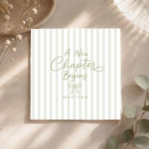 May include: A square card featuring a light green and white vertical striped pattern. The text A New Chapter Begins is printed in a sage green script font above a small line-drawn bow icon and the name MADISON in a simple sans-serif font.