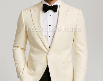 May include: Ivory-colored tuxedo jacket with a black bow tie and black trousers. The jacket has a single-button closure and a notched lapel. The Groom House text is visible on the jacket.